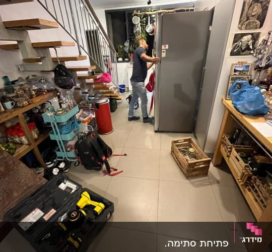 אדם בודק מקרר עם כלים לתיקון נזילות